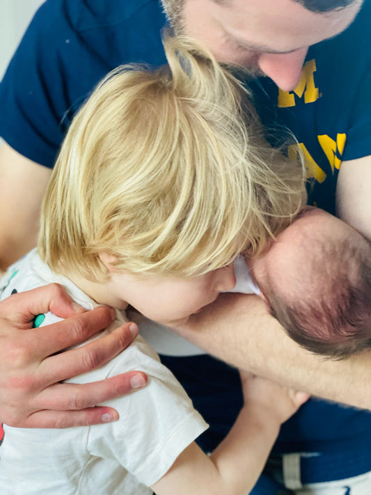 father-hugging-newborn-baby-and-toddler-looking-down-at-baby-bon-and-bear