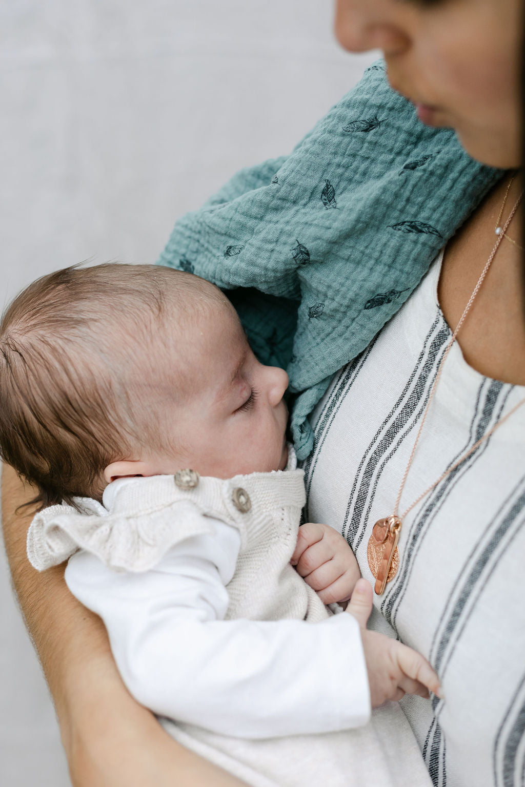 baby-sleeping-in-mums-arms-with-green-feather-print-muslin-over-shoulder-bon-and-bear