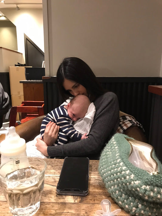 mum-looking-down-whilst-kissing-newborn-baby-on-head-with-bottle-andwater-on-table-bon-and-bear