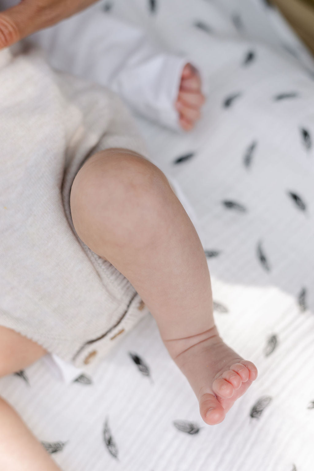 baby-leg-and-toes-bent-on-white-printed-feather-muslin-blanket-bon-and-bear