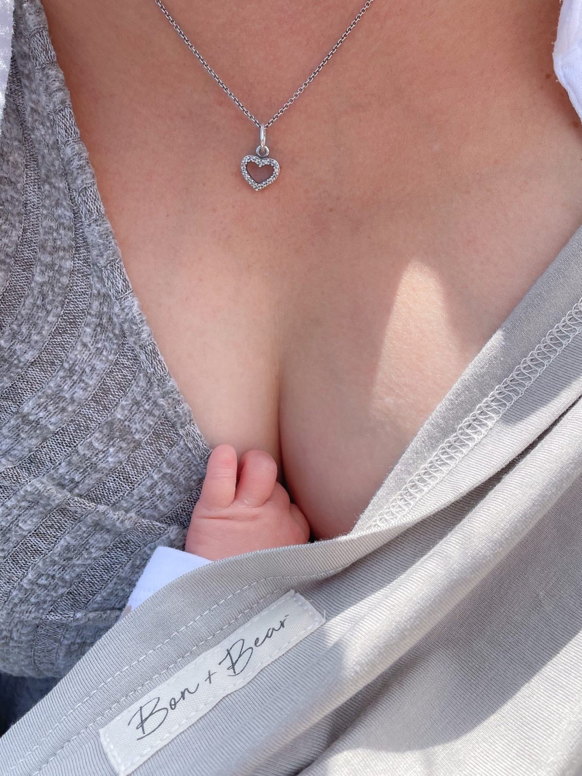 close-up-of-mum-breastfeeding-baby-with-oat-beige-cover-and-small-baby-hand-holding-top-bon-and-bear