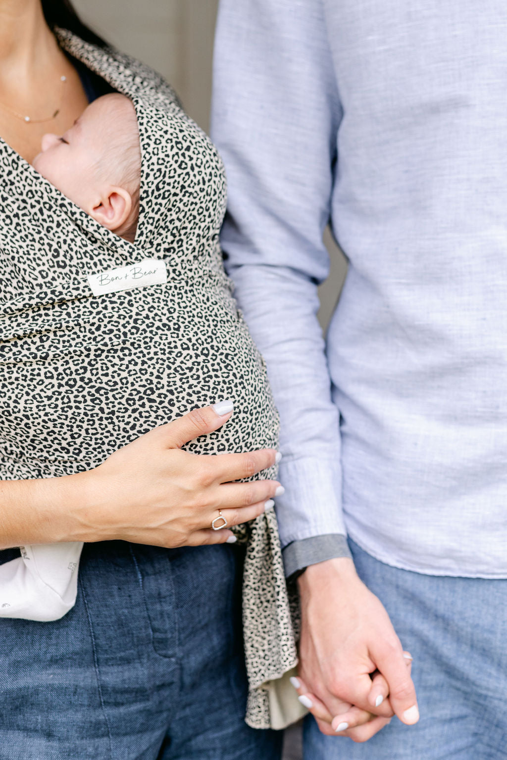 mother-and-father-holding-hands-with-mum-carrying-baby-in-leoaprd-print-wrap-bon-and-bear