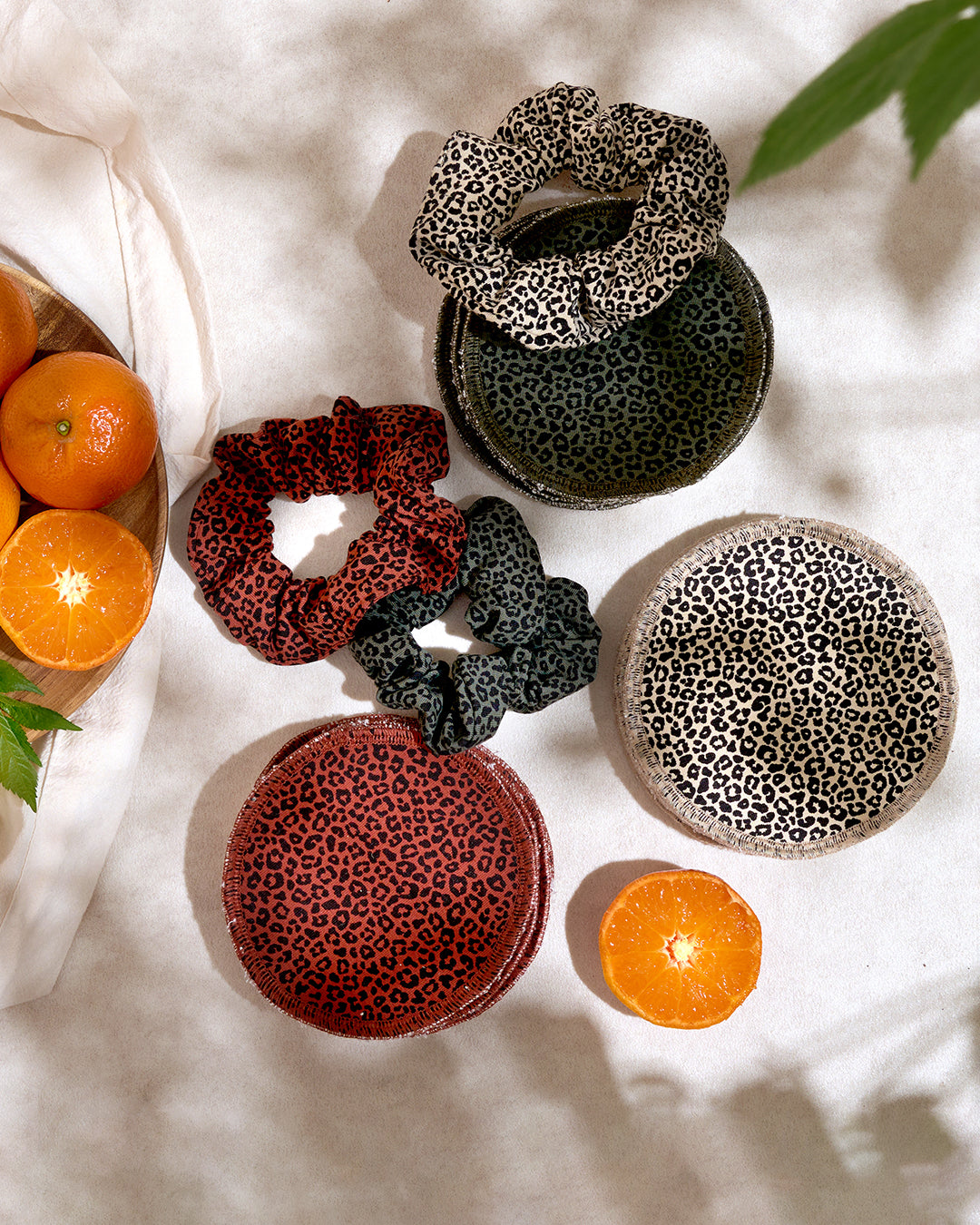 beige-green-red-leoaprd-print-reusable-bamboo-cotton-breastpads-on-linen-tablecloth-with-oranges-to-the-side